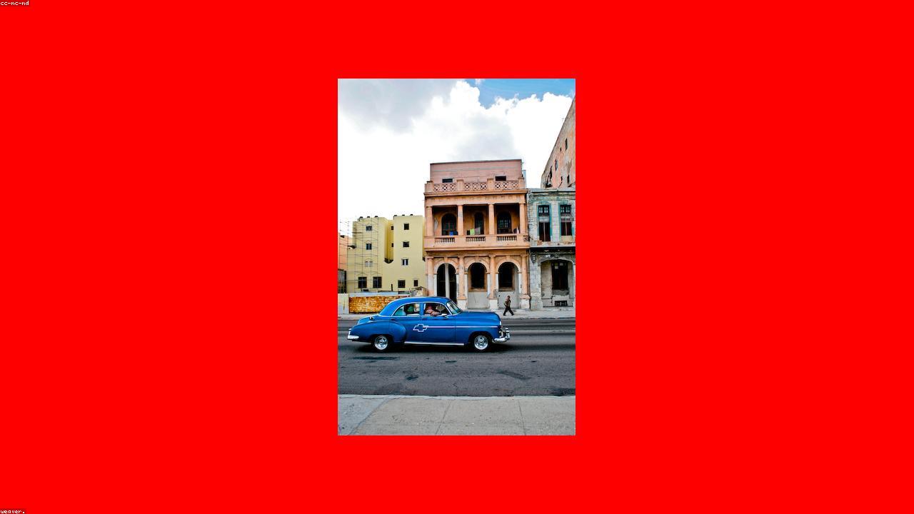 A vintage Chevrolet drives past pastel colonial façades in Old Havana.