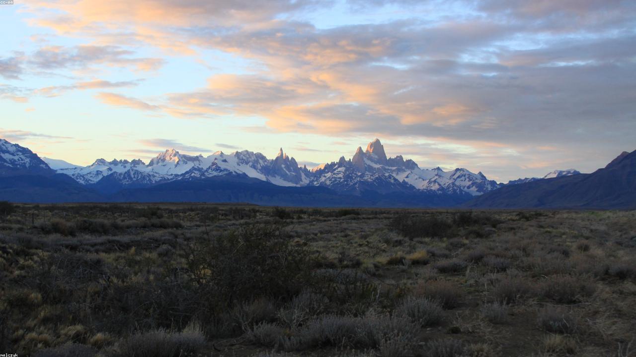 Granite spires of Fitz Roy reflect in a still alpine lake.