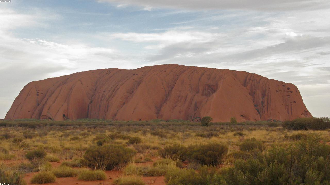 Uluru glows deep red against a cobalt sky at dawn.